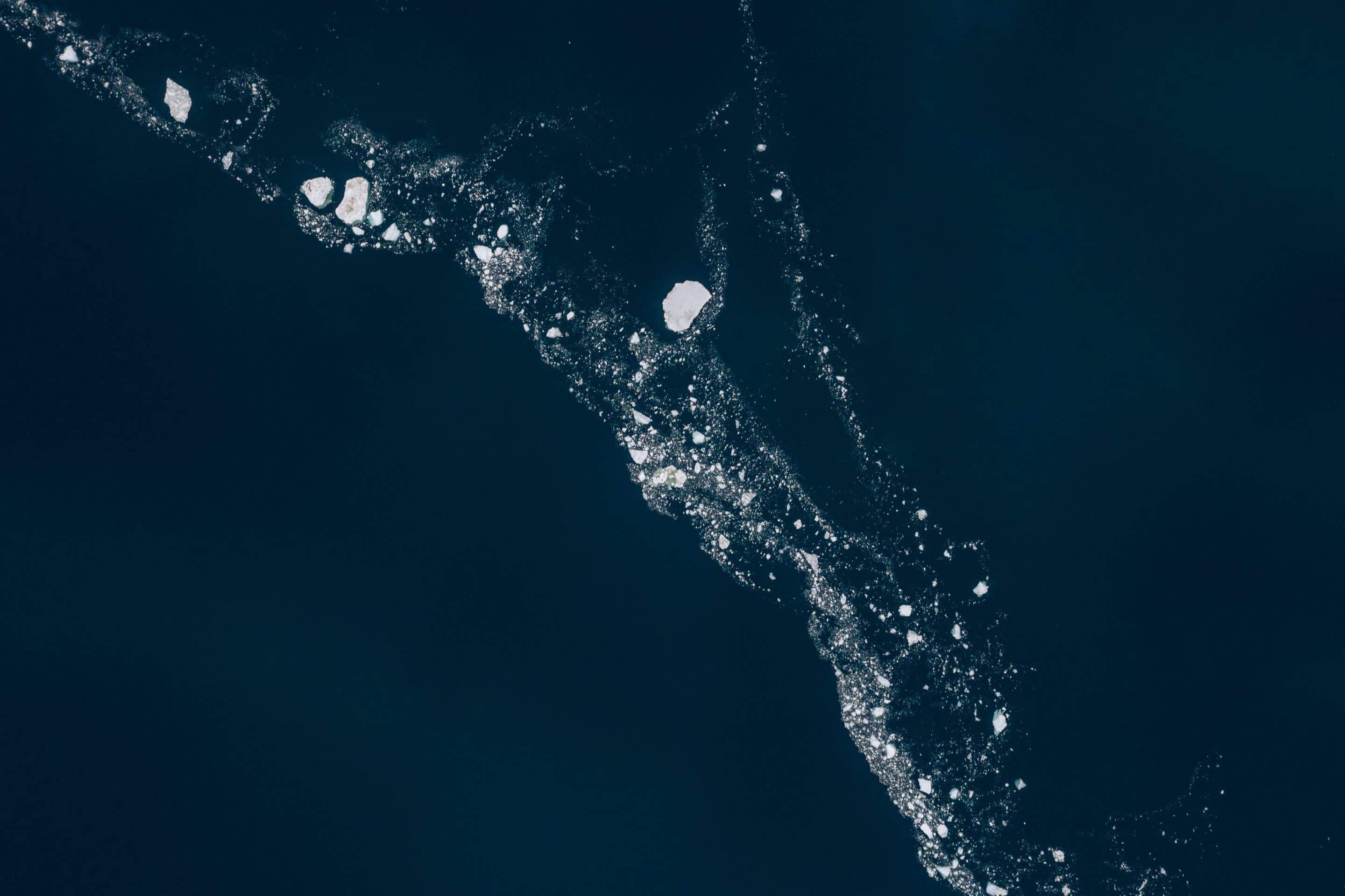 Fine art aerial photography series that sees the sea ice in Greenland as stars and galaxies that are forming a universe in the calm Atlantic ocean by Michael Schauer