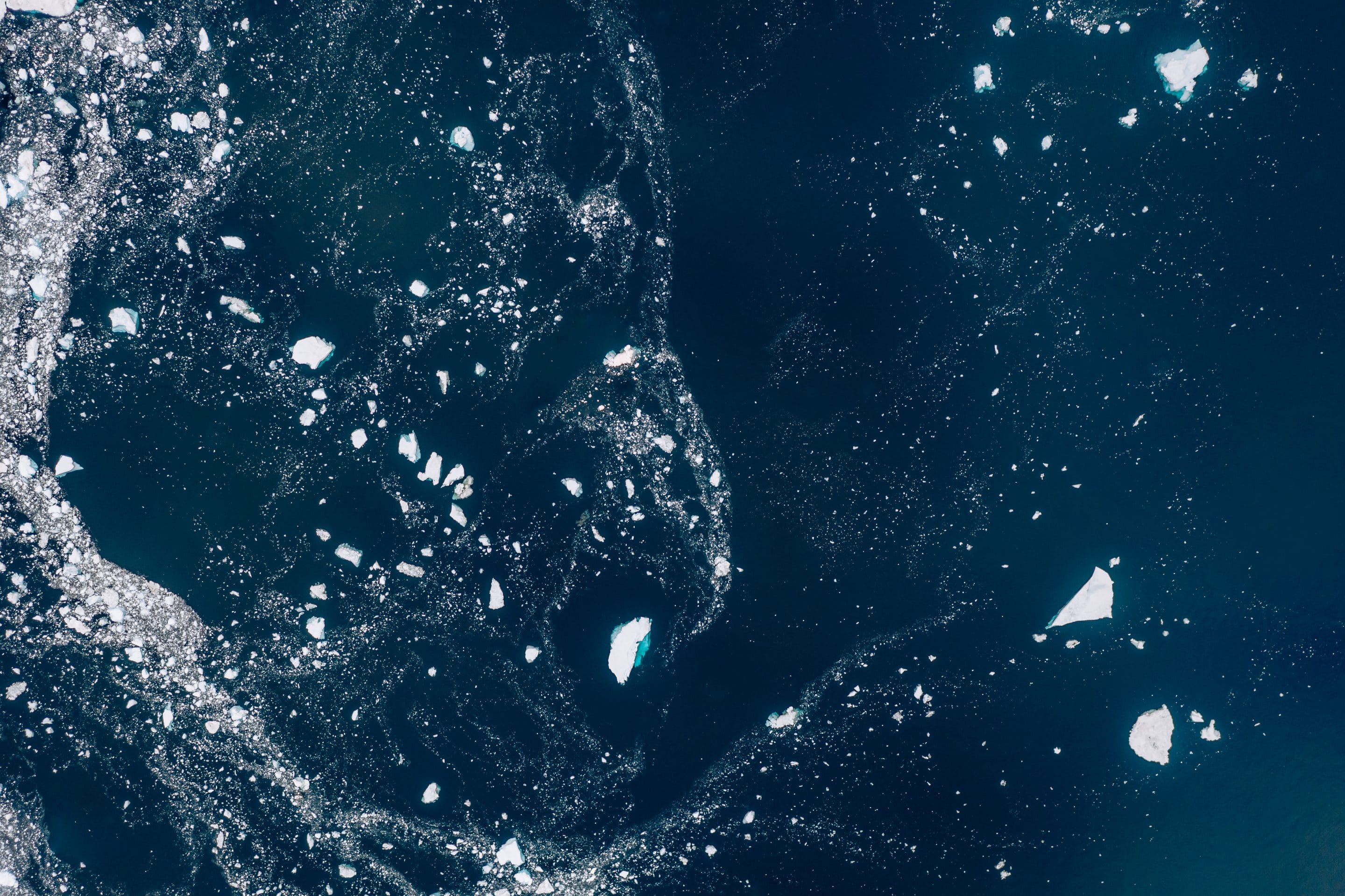 Fine art aerial photography series that sees the sea ice in Greenland as stars and galaxies that are forming a universe in the calm Atlantic ocean by Michael Schauer