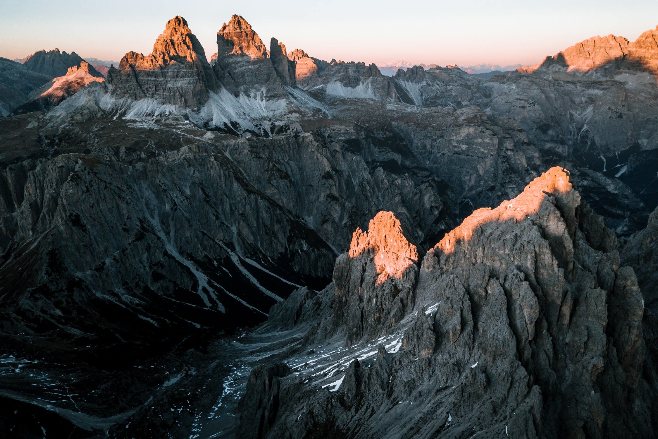A beautiful sunset lights up the landscape in the Italian Dolomites shining a warm, orange light on the Tre Cime mountains. By photographer Michael Schauer